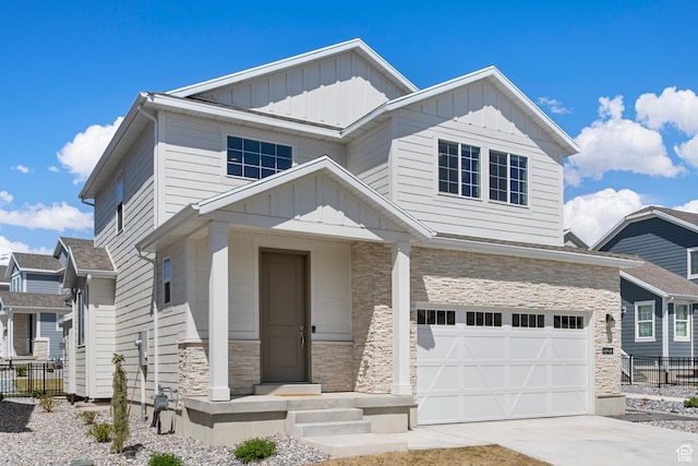 craftsman-style home with board and batten siding, fence, stone siding, concrete driveway, and an attached garage
