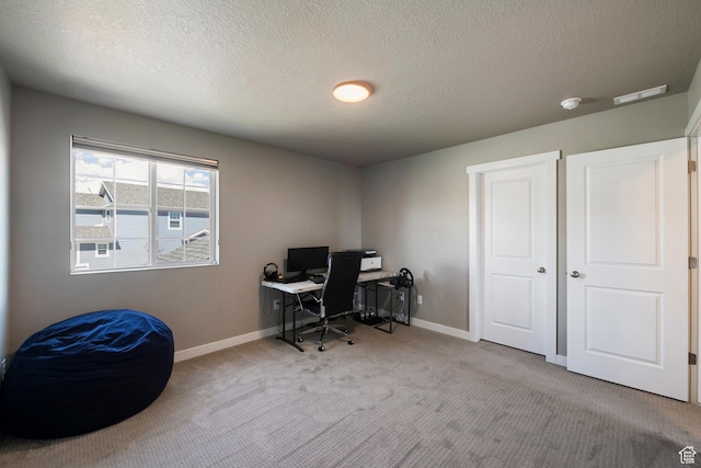 carpeted office with baseboards, visible vents, and a textured ceiling