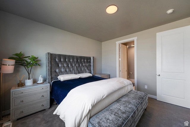 bedroom featuring baseboards, dark colored carpet, and ensuite bath