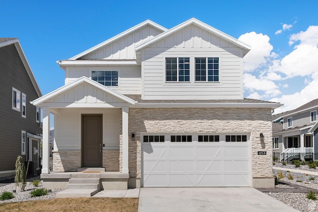 view of front of home with concrete driveway, stone siding, an attached garage, and board and batten siding
