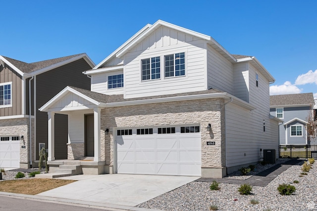 view of front of house with concrete driveway, board and batten siding, stone siding, an attached garage, and fence