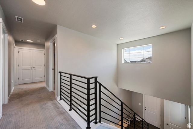 corridor featuring visible vents, an upstairs landing, carpet floors, and recessed lighting