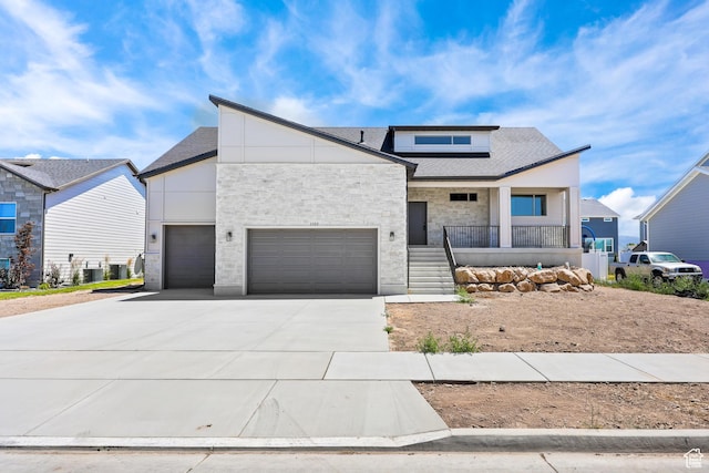 1107 S 4475 W, West Point, UT 84015 - modern home featuring covered porch, driveway, stone siding, solar panels, and a shingled roof