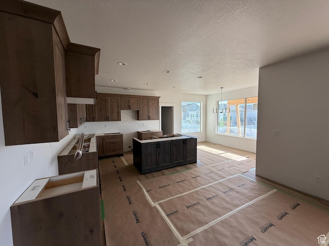 1107 S 4475 W, West Point, UT 84015 - kitchen featuring a textured ceiling, recessed lighting, a kitchen island, light wood-style flooring, and hanging light fixtures