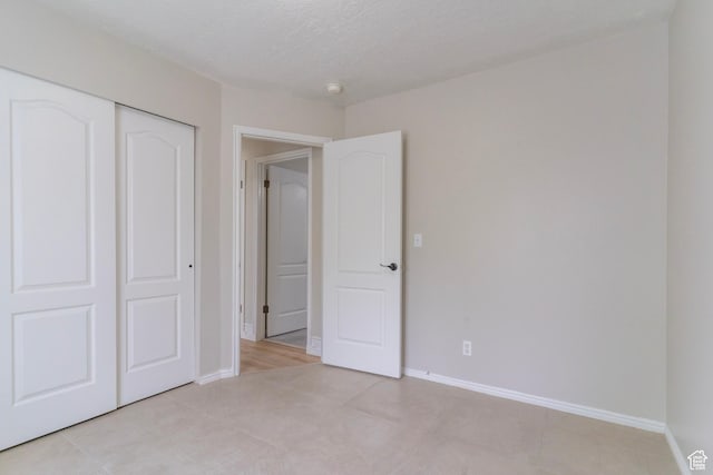 1608 W 8470 S, West Jordan, UT 84088 - unfurnished bedroom featuring baseboards, light tile patterned floors, a textured ceiling, and a closet