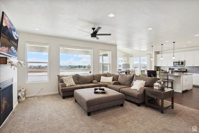 3339 W 650 N, Layton, UT 84041 - living room with recessed lighting, a ceiling fan, dark colored carpet, a lit fireplace, and a textured ceiling