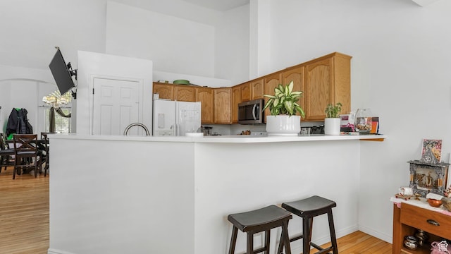 450 E Waterford Way, Midvale, UT 84047 - kitchen featuring stainless steel microwave, a kitchen breakfast bar, light wood-type flooring, a towering ceiling, and freestanding refrigerator