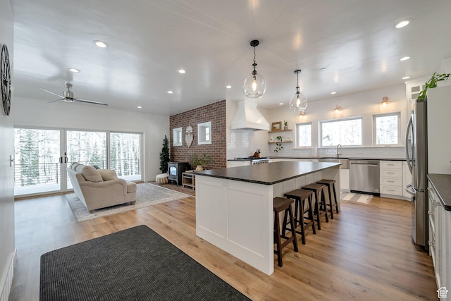 4460 Fawn Way Unit 2039, Heber City, UT 84032 - kitchen with a wood stove, dark countertops, a breakfast bar area, custom range hood, and stainless steel appliances