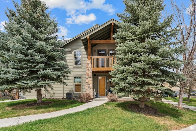 view of front of house featuring central AC unit, a balcony, and a front yard