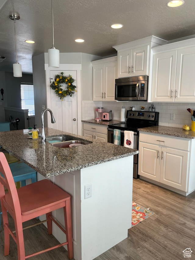 864 E 180 N, Salem, UT 84653 - kitchen with a sink, stainless steel appliances, dark stone countertops, light wood-style flooring, and white cabinetry