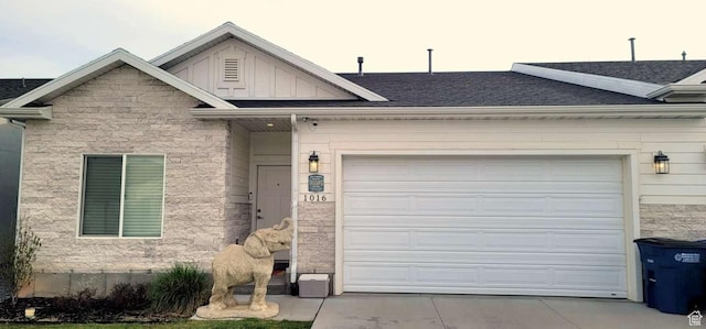 view of front of house with a garage, stone siding, a shingled roof, board and batten siding, and driveway