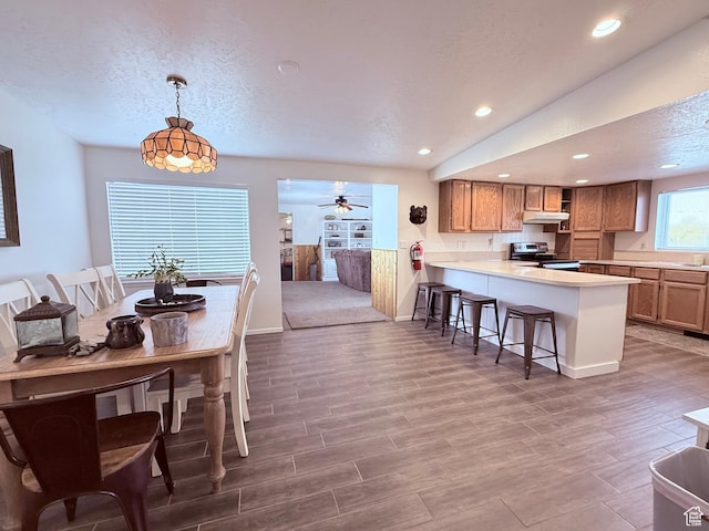 1705 S Bear Lake Blvd, Garden City, UT 84028 - kitchen with a ceiling fan, stainless steel electric range oven, a peninsula, a breakfast bar, and under cabinet range hood