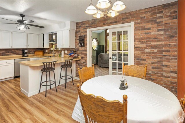 33 S Benchview Dr E, Tooele, UT 84074 - dining room with ceiling fan with notable chandelier, light wood finished floors, and brick wall