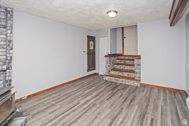 33 S Benchview Dr E, Tooele, UT 84074 - unfurnished living room featuring baseboards, a wood stove, a textured ceiling, and wood finished floors