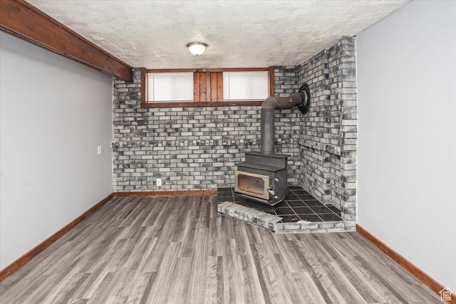 33 S Benchview Dr E, Tooele, UT 84074 - basement featuring baseboards, a wood stove, a textured ceiling, and wood finished floors