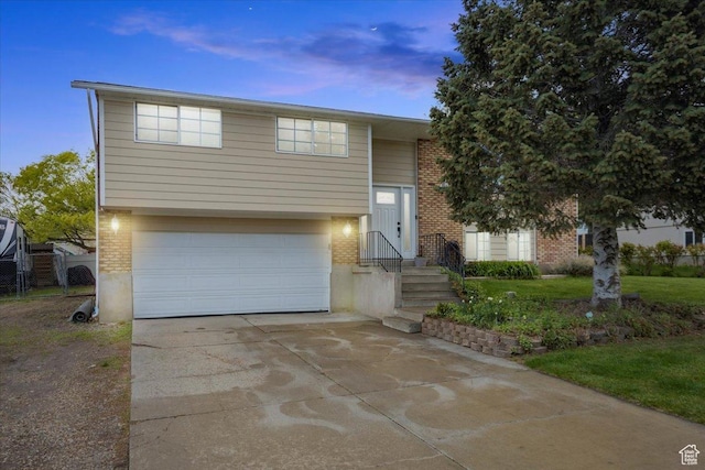raised ranch featuring brick siding, a garage, and driveway