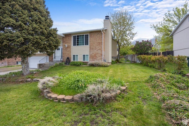 33 S Benchview Dr E, Tooele, UT 84074 - split foyer home featuring a chimney, brick siding, fence, a front lawn, and an attached garage