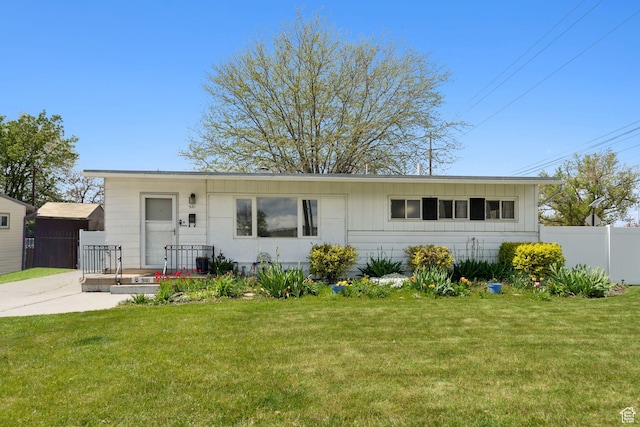 single story home with board and batten siding, fence, and a front yard