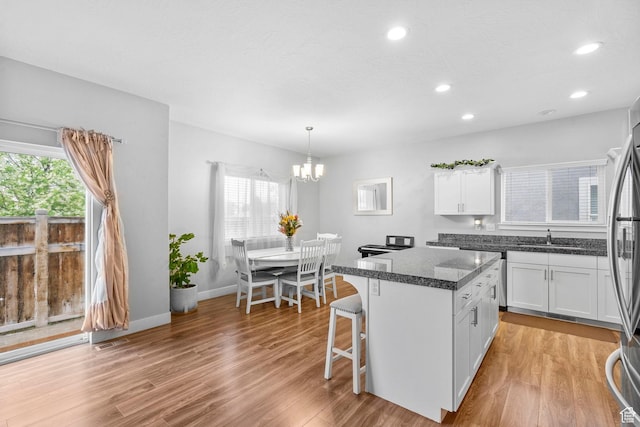 7465 N Cottage Ln, Eagle Mountain, UT 84005 - kitchen with a notable chandelier, a sink, light wood-style flooring, white cabinetry, and visible vents