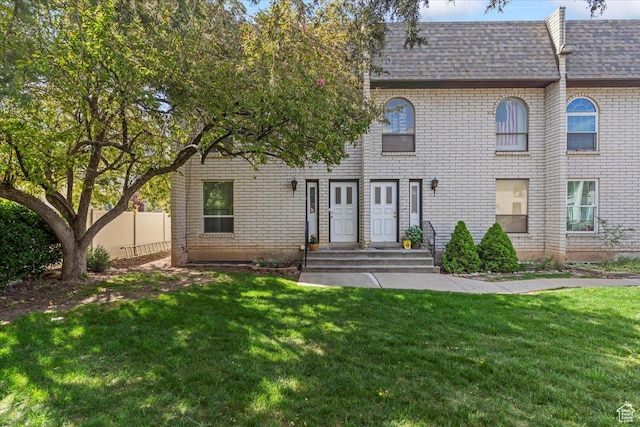 1554 S Monroe Blvd Unit F4, Ogden, UT 84404 - view of front of home featuring brick siding, fence, a shingled roof, and a front lawn