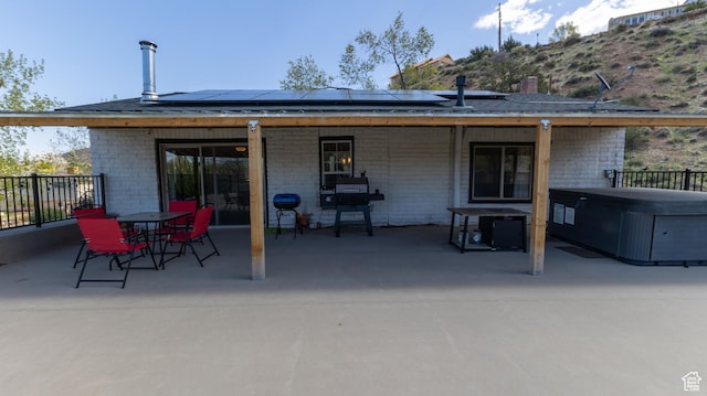 450 Hillside Pl, Cedar City, UT 84721 - rear view of property featuring roof mounted solar panels, a patio, a hot tub, and brick siding
