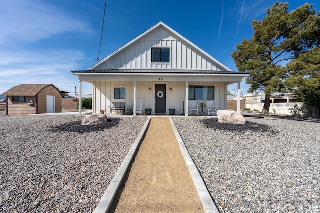 bungalow-style house with a storage shed, an outbuilding, board and batten siding, and a porch