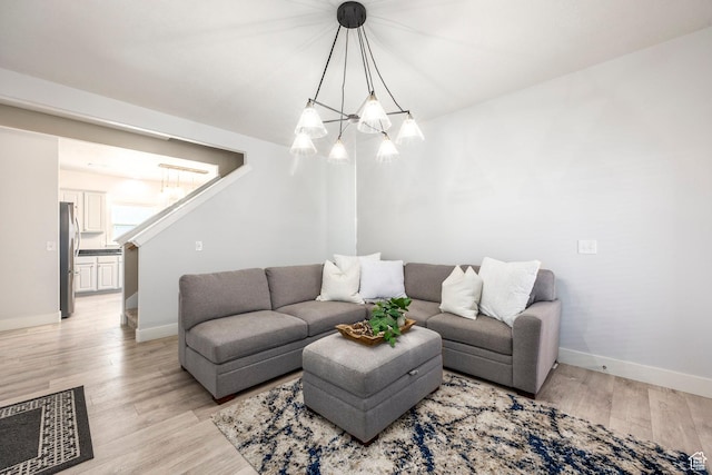 living room with light wood-style floors, baseboards, and an inviting chandelier