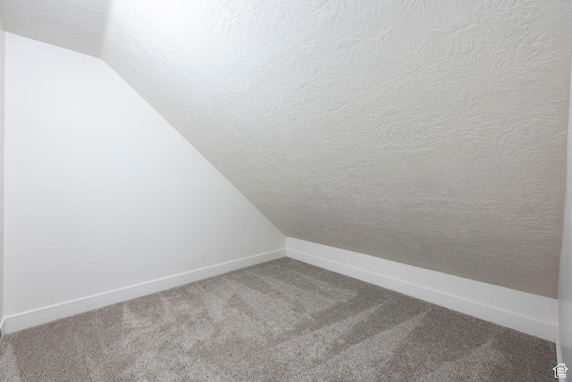 bonus room featuring a textured ceiling, carpet, baseboards, and lofted ceiling