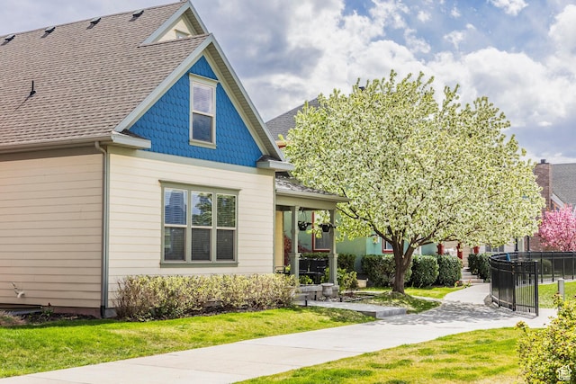 view of front of property featuring fence, a shingled roof, and a front yard