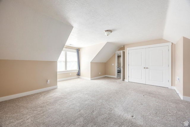 bonus room featuring baseboards, carpet flooring, a textured ceiling, and vaulted ceiling