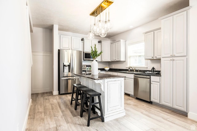 kitchen with light wood-style floors, appliances with stainless steel finishes, a center island, and a breakfast bar
