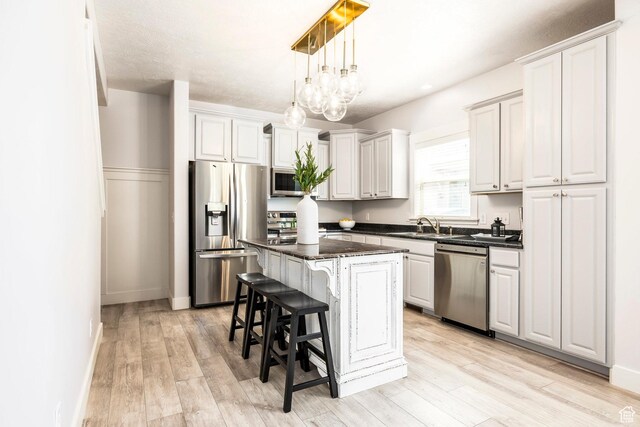 4306 Degray Dr, South Jordan, UT 84095 - kitchen with stainless steel appliances, a kitchen island, a breakfast bar, and light wood finished floors