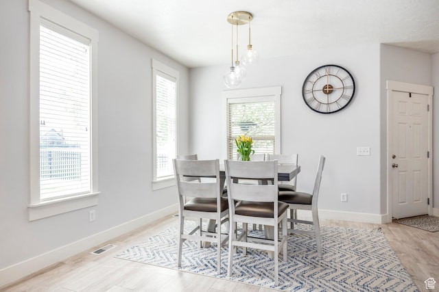 dining space with light wood-style floors, baseboards, and visible vents