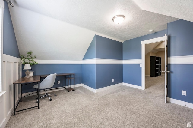 carpeted office featuring a textured ceiling, baseboards, and lofted ceiling
