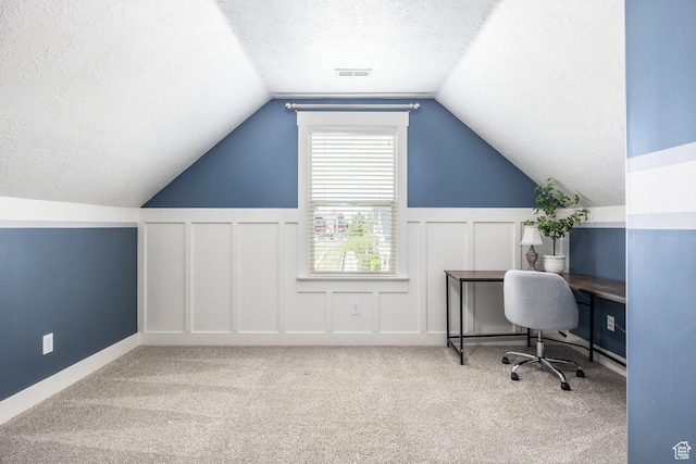 home office with carpet flooring, a textured ceiling, a decorative wall, and lofted ceiling