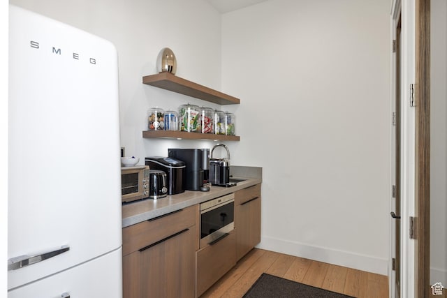 4554 N Forestdale Dr Unit A1, Park City, UT 84098 - kitchen with open shelves, light countertops, freestanding refrigerator, stainless steel microwave, and light wood finished floors