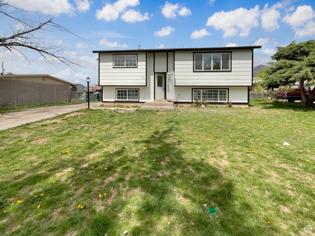 bi-level home with fence, a front yard, and concrete driveway