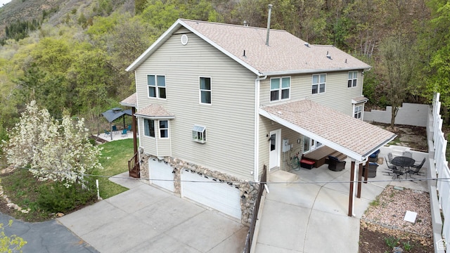 3841 E Grindstone Dr S, Springville, UT 84663 - rear view of house featuring driveway, fence, an attached garage, a shingled roof, and stone siding