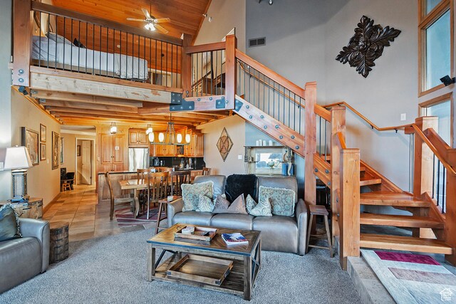 living room with light carpet, high vaulted ceiling, ceiling fan with notable chandelier, visible vents, and stairway