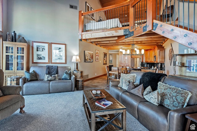 living area featuring baseboards, a high ceiling, a chandelier, and visible vents