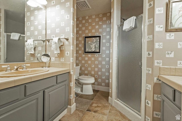 full bath with vanity, baseboards, a shower stall, and toilet