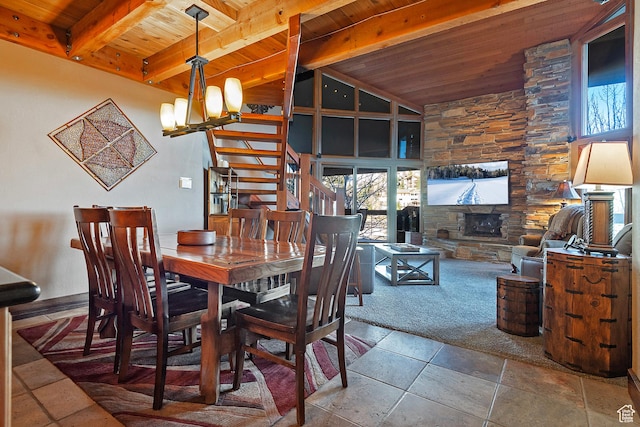 dining room with stone tile flooring, wood ceiling, stairway, and a stone fireplace