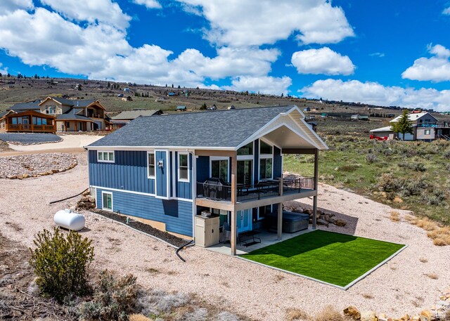 2774 S Chukar Dr, Garden City, UT 84028 - back of property featuring roof with shingles, board and batten siding, a deck, a patio area, and a yard