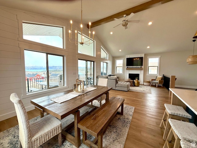2774 S Chukar Dr, Garden City, UT 84028 - dining room featuring a large fireplace, beam ceiling, high vaulted ceiling, ceiling fan with notable chandelier, and light wood-style flooring