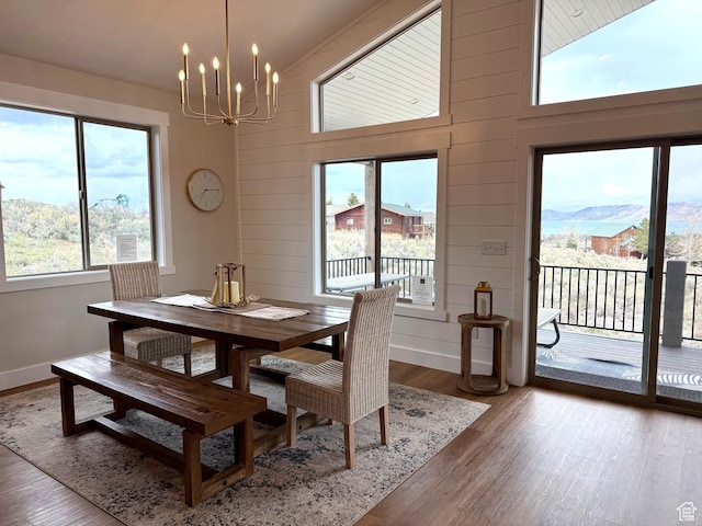 2774 S Chukar Dr, Garden City, UT 84028 - dining room with baseboards, a high ceiling, wooden walls, light wood finished floors, and a notable chandelier
