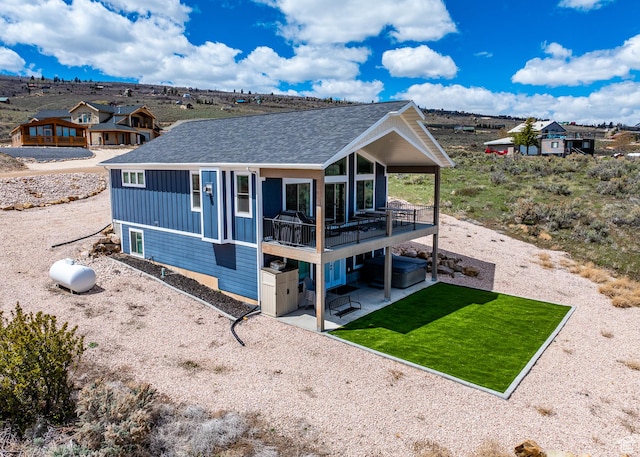 2774 S Chukar Dr, Garden City, UT 84028 - back of property with board and batten siding, roof with shingles, a lawn, a wooden deck, and a patio area