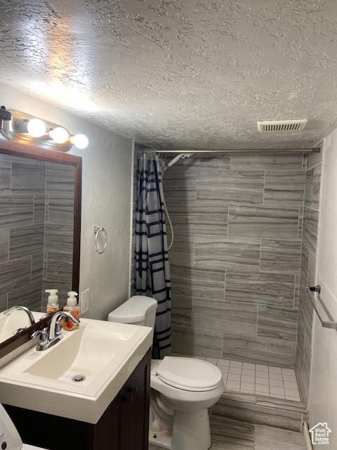 2622 N 175 W, Sunset, UT 84015 - bathroom featuring a textured ceiling, a tile shower, vanity, toilet, and wood finished floors