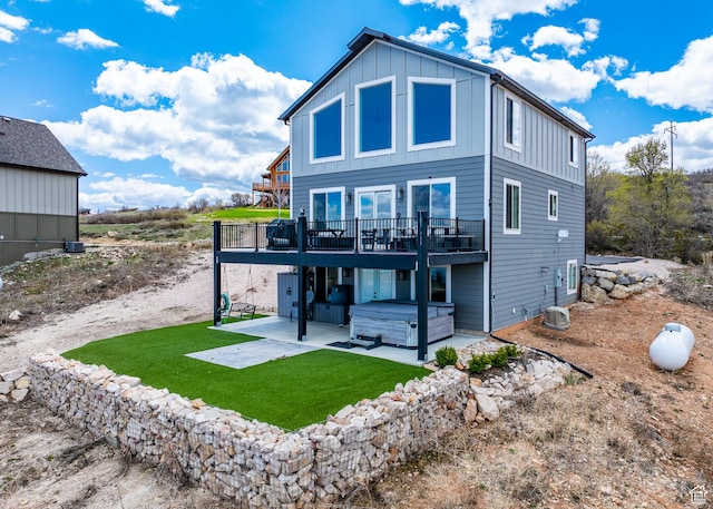 660 N Cambry Dr, Garden City, UT 84028 - rear view of property featuring a hot tub, a wooden deck, board and batten siding, a lawn, and a patio