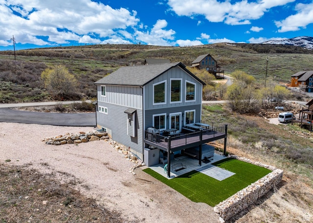 660 N Cambry Dr, Garden City, UT 84028 - rear view of house with a patio area, board and batten siding, a deck with mountain view, and a lawn