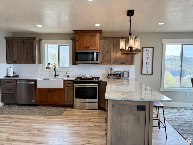 660 N Cambry Dr, Garden City, UT 84028 - kitchen featuring a breakfast bar area, appliances with stainless steel finishes, a sink, a peninsula, and light wood-style floors